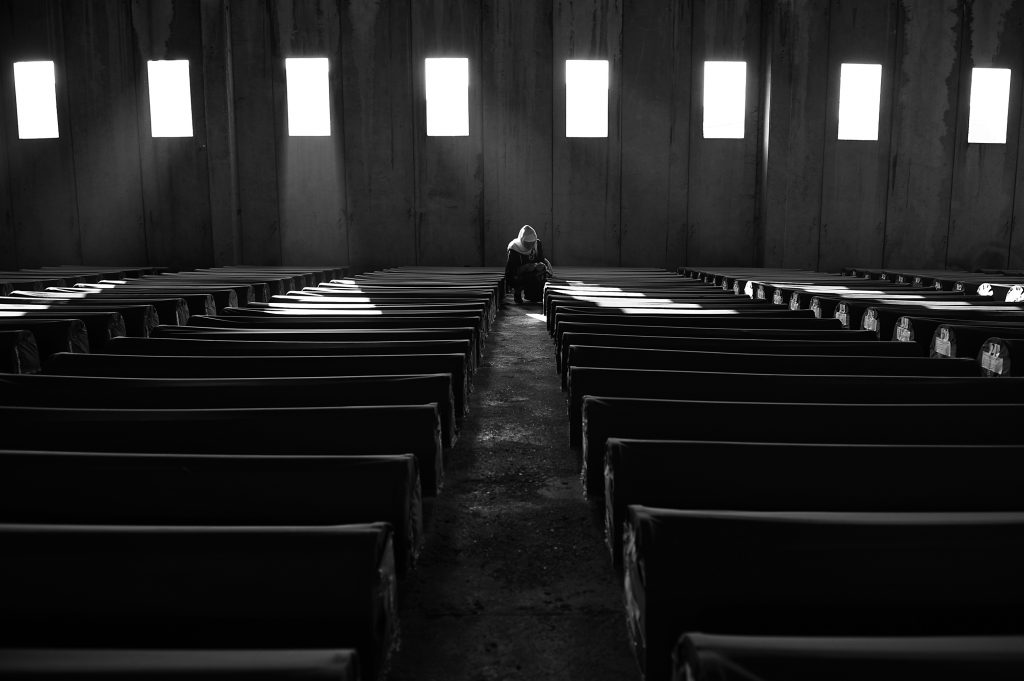 A Bosnian Muslim woman prays near the coffin of a loved one. She is surrounded by the identified bodies of victims of the Srebrenica genocide, which are stored in the abandoned hall of the car battery factory in Potočari in preparation for the yearly burial ceremony that takes place on 11 July. (Photo: Midhat Poturović)